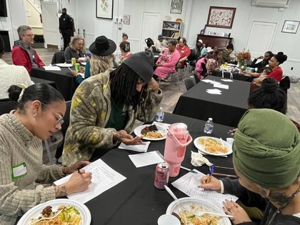 People sit around tables with food and notes in front of them