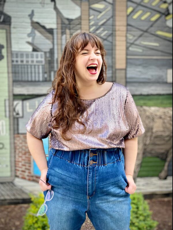 Eliana Light in iridescent top and jeans, lauging