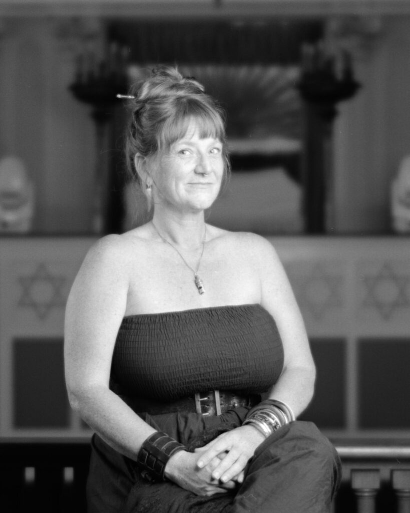 Black and white photo of a person wearing a strapless top with hair piled on top of their head looking at the camear