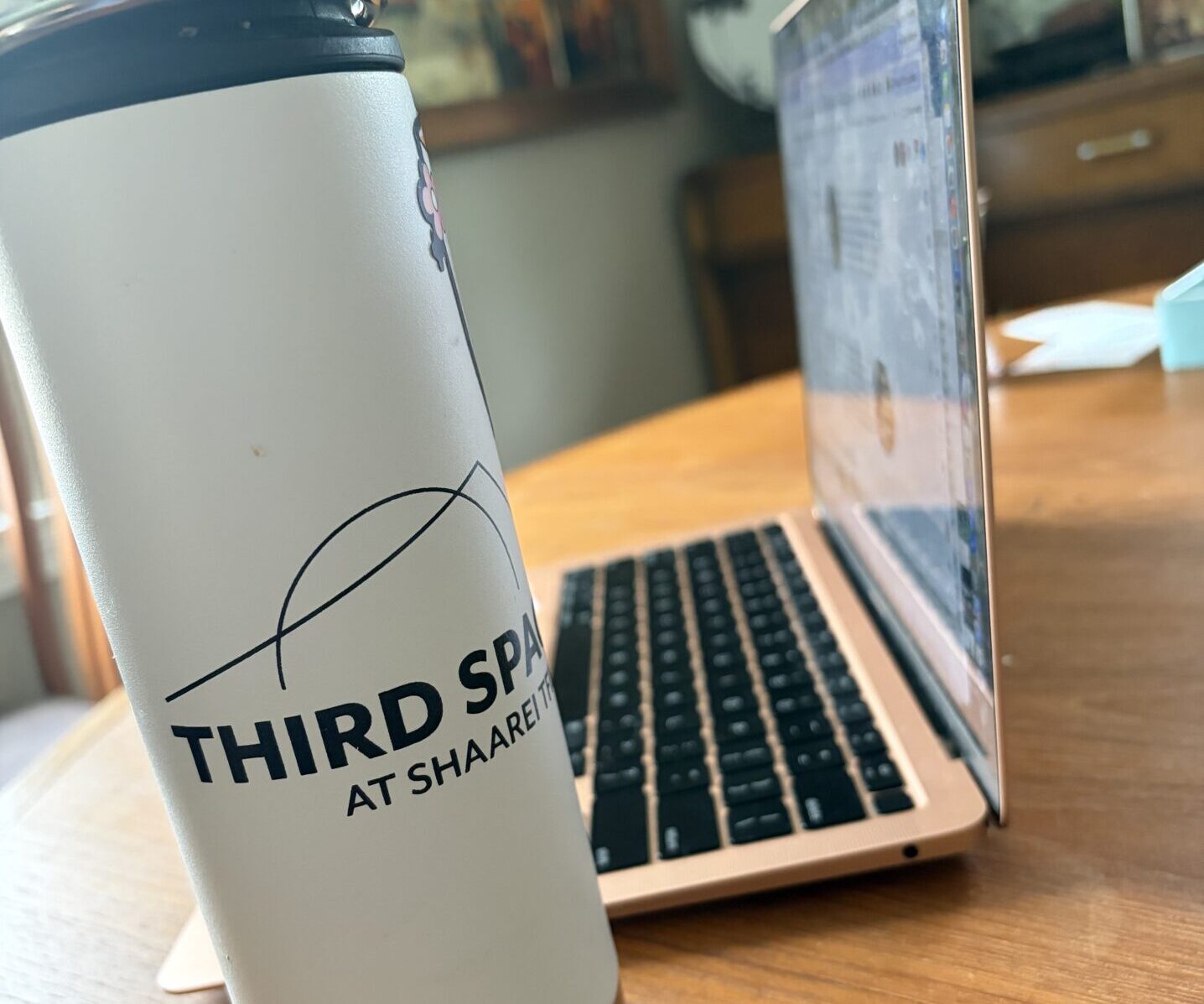 A third space travel mug beside an open laptop