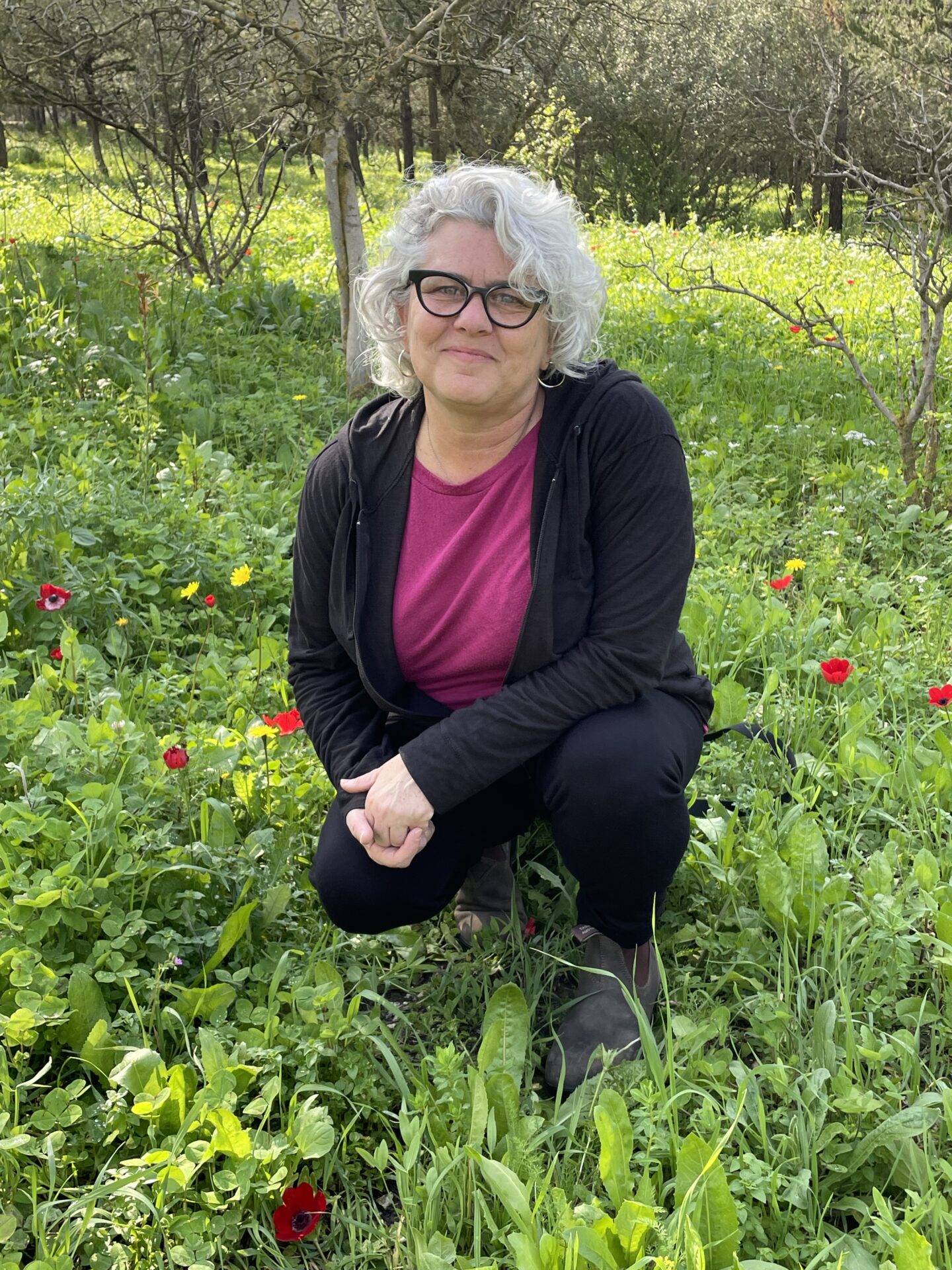Rabbi Elissa Sachs-Kohen kneeling in a field of green grass