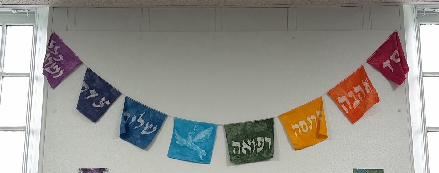 rainbow prayer flags with Jewish symbols and Hebrew writing